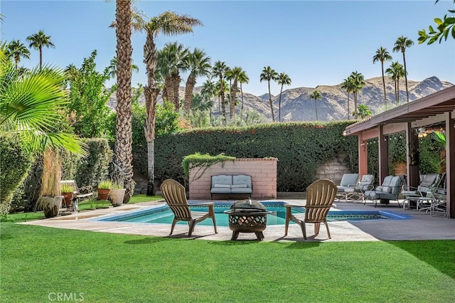 view of swimming pool with a mountain view, a patio, a fire pit, and a lawn