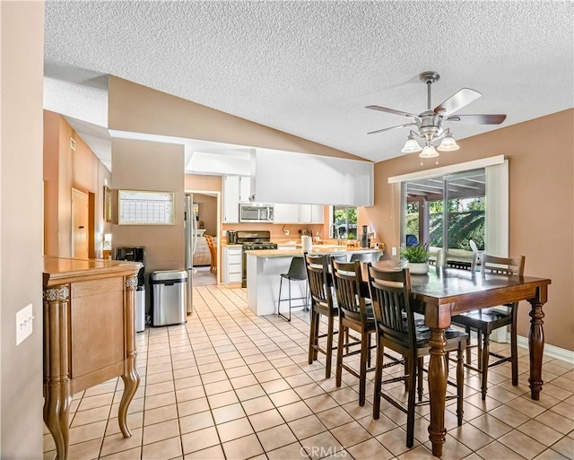 tiled dining room featuring ceiling fan, a textured ceiling, and vaulted ceiling