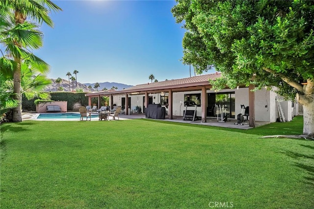 back of property featuring a mountain view, a yard, and a patio area