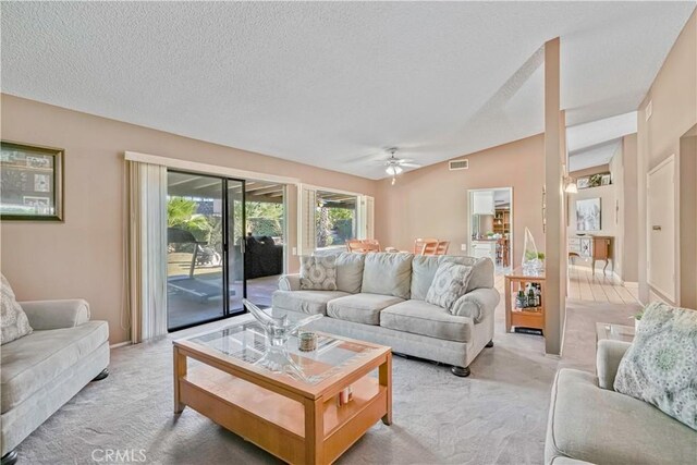 carpeted living room featuring a textured ceiling, vaulted ceiling, and ceiling fan