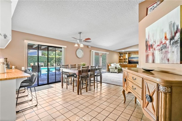 tiled dining room featuring ceiling fan, a textured ceiling, and vaulted ceiling