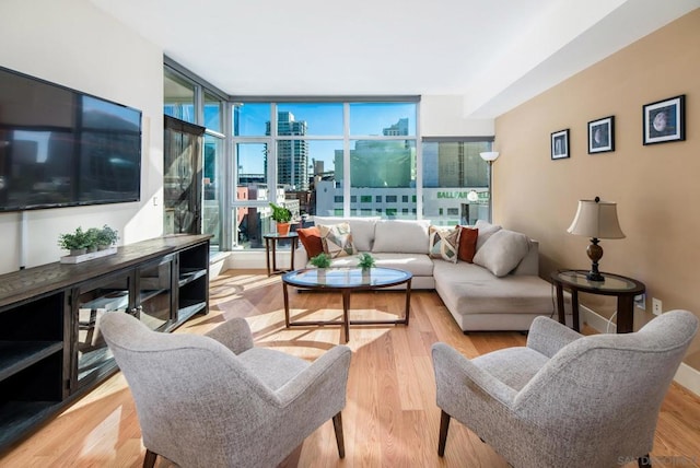 living room with light hardwood / wood-style flooring, a wall of windows, and a healthy amount of sunlight