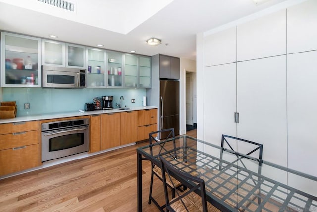 kitchen with light hardwood / wood-style floors, sink, and stainless steel appliances