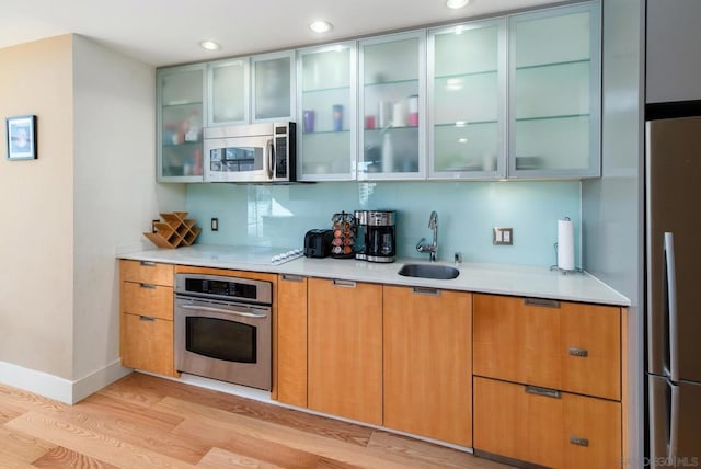 kitchen with backsplash, light hardwood / wood-style flooring, stainless steel appliances, and sink