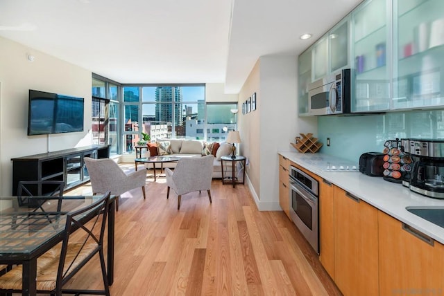 kitchen featuring appliances with stainless steel finishes, light hardwood / wood-style floors, and expansive windows