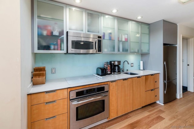 kitchen featuring light wood-type flooring, sink, and appliances with stainless steel finishes