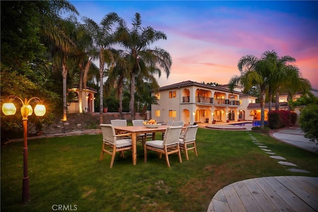 yard at dusk featuring a balcony and a patio