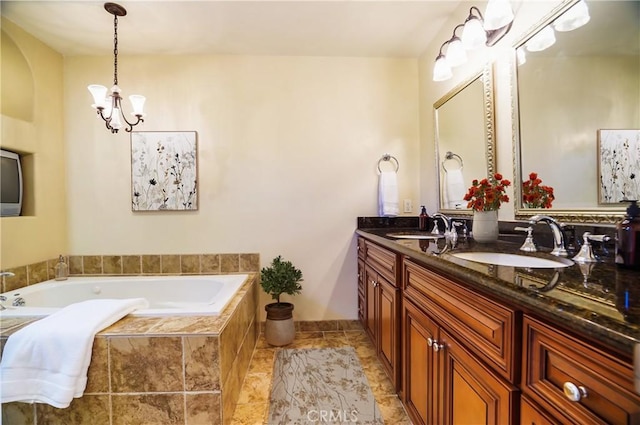 bathroom with a chandelier, vanity, and tiled bath