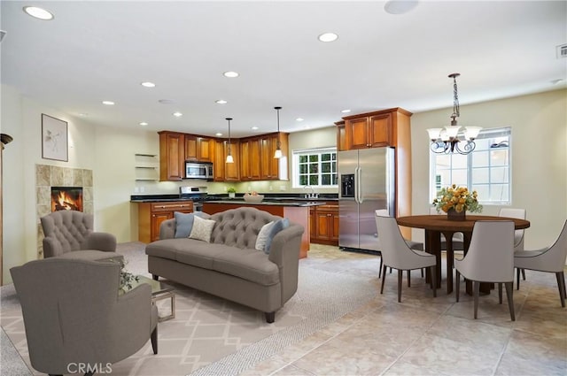 interior space featuring stainless steel appliances, a notable chandelier, pendant lighting, a fireplace, and light tile patterned floors