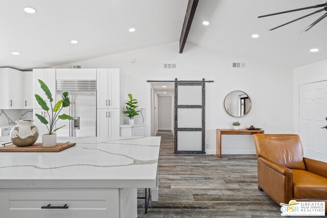 kitchen featuring a barn door, lofted ceiling with beams, dark hardwood / wood-style floors, built in refrigerator, and white cabinets