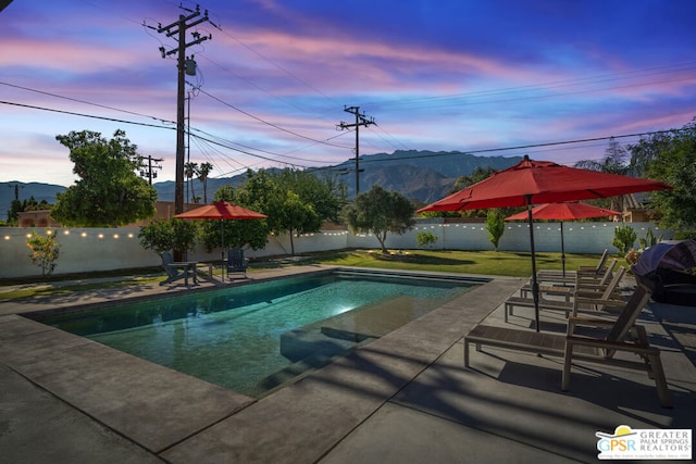 pool at dusk with a patio area and a mountain view