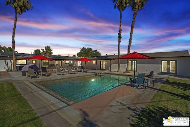 pool at dusk with a patio area and french doors