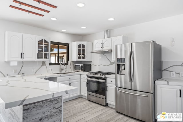 kitchen featuring white cabinetry, sink, light stone countertops, and appliances with stainless steel finishes