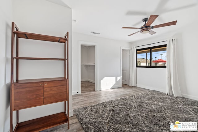 bedroom featuring a closet, dark hardwood / wood-style floors, a spacious closet, and ceiling fan