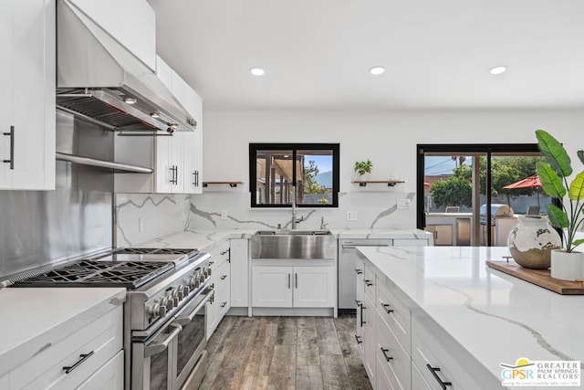 kitchen with hardwood / wood-style floors, double oven range, wall chimney range hood, and a wealth of natural light