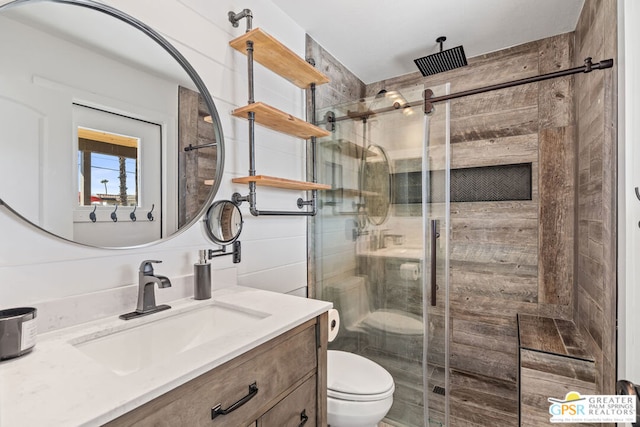 bathroom with a shower with door, vanity, and toilet