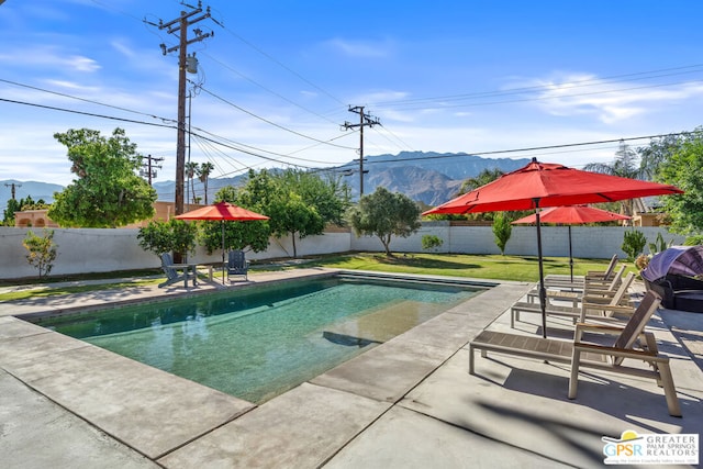 view of pool with a mountain view, a yard, and a patio