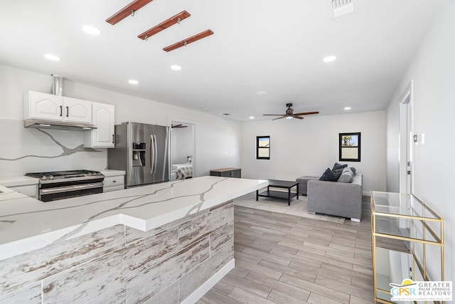 kitchen featuring ceiling fan, light stone countertops, appliances with stainless steel finishes, light hardwood / wood-style floors, and white cabinetry