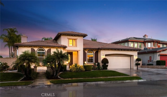 mediterranean / spanish-style home featuring a garage and a lawn