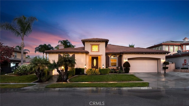 mediterranean / spanish home with a garage and a lawn