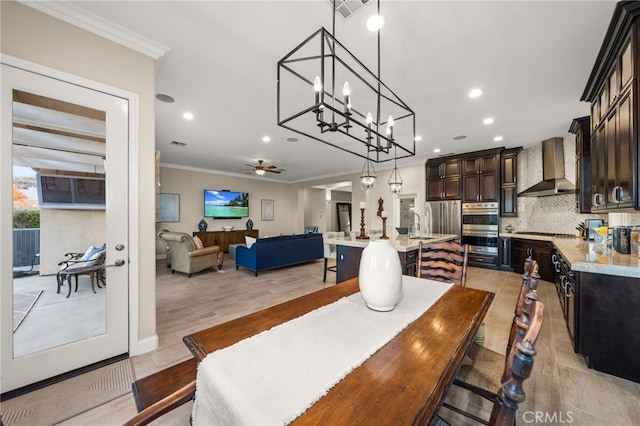 dining space featuring ceiling fan, sink, crown molding, and light hardwood / wood-style flooring