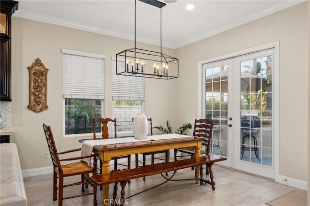 dining room featuring french doors, light wood-type flooring, a notable chandelier, and ornamental molding