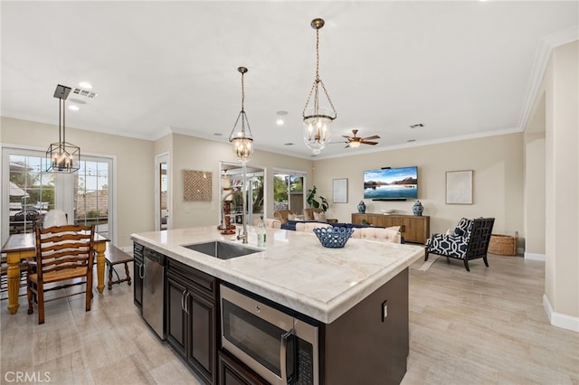 kitchen featuring a wealth of natural light, a kitchen island with sink, sink, and appliances with stainless steel finishes