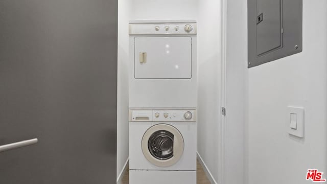 clothes washing area featuring stacked washer / drying machine and electric panel