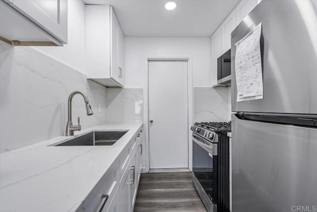 kitchen with sink, dark hardwood / wood-style floors, decorative backsplash, appliances with stainless steel finishes, and white cabinetry