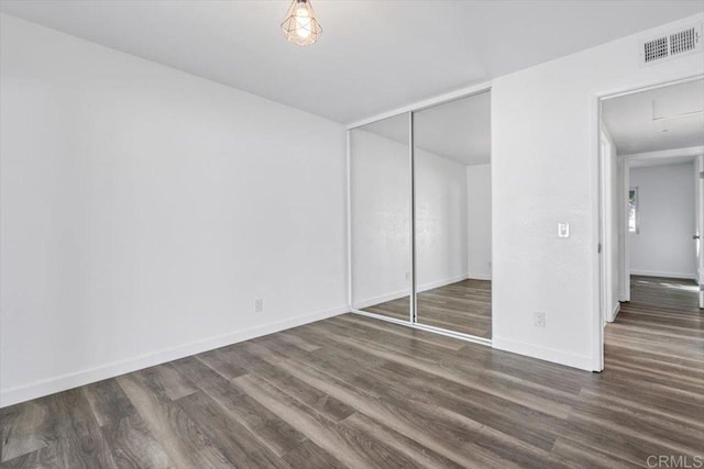 unfurnished bedroom with dark hardwood / wood-style floors and a closet