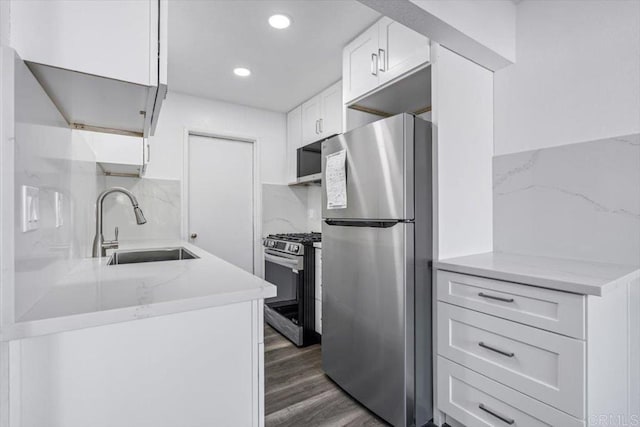 kitchen with dark wood-type flooring, white cabinets, sink, decorative backsplash, and stainless steel appliances