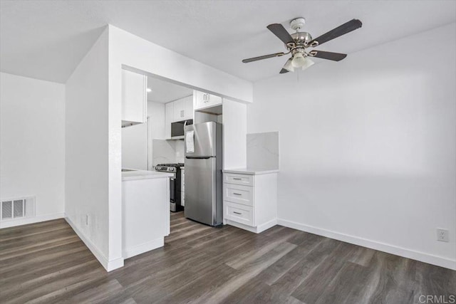 kitchen with white cabinets, appliances with stainless steel finishes, dark hardwood / wood-style flooring, and ceiling fan