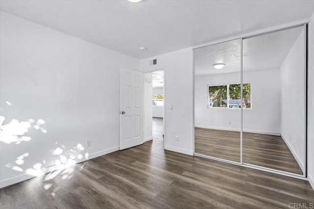 unfurnished bedroom with a closet and dark wood-type flooring