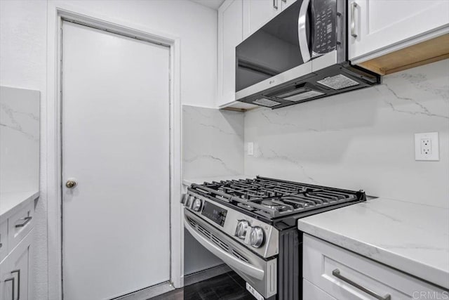 kitchen featuring decorative backsplash, light stone counters, stainless steel appliances, wood-type flooring, and white cabinetry