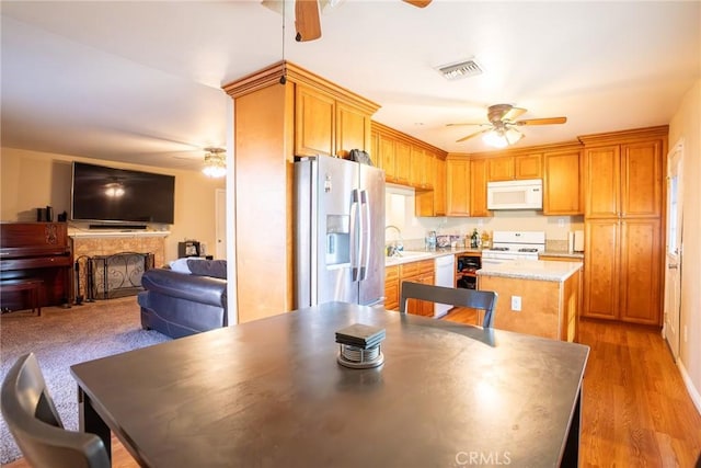 kitchen with white appliances, light hardwood / wood-style floors, a kitchen island, and sink