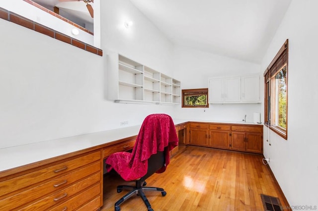 office featuring light hardwood / wood-style floors, sink, built in desk, and vaulted ceiling