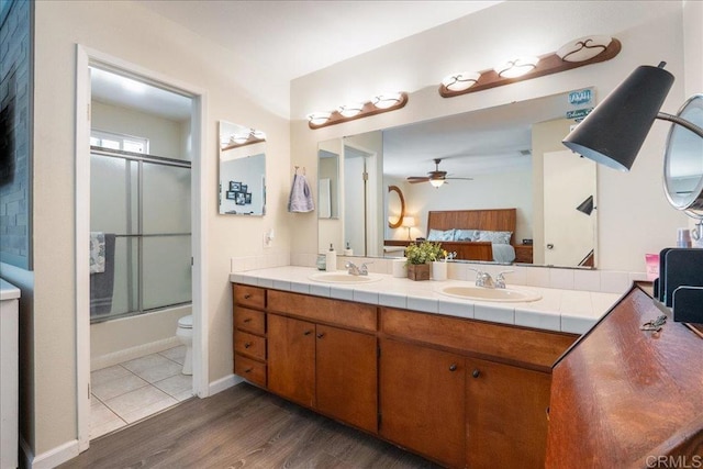 full bathroom with vanity, combined bath / shower with glass door, ceiling fan, toilet, and wood-type flooring