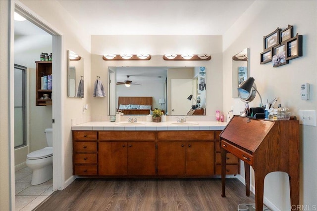 full bathroom featuring vanity, ceiling fan, wood-type flooring, enclosed tub / shower combo, and toilet