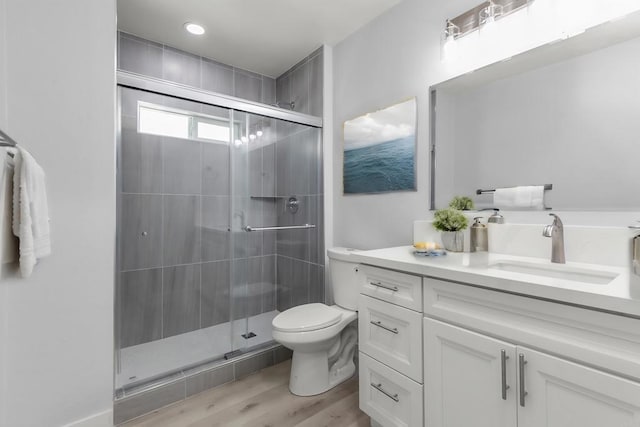 bathroom with toilet, vanity, a shower with shower door, and hardwood / wood-style flooring