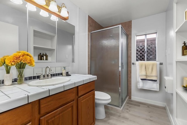 bathroom with toilet, a shower with door, vanity, and hardwood / wood-style flooring