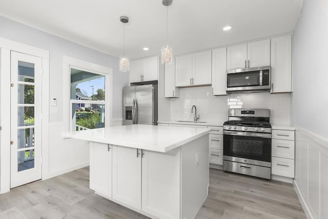 kitchen featuring appliances with stainless steel finishes, white cabinetry, a kitchen island, and sink