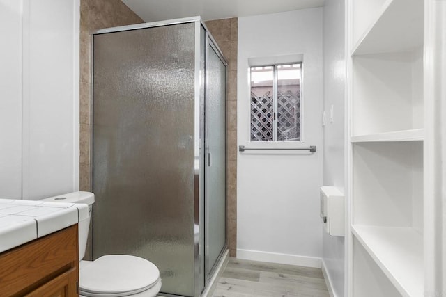 bathroom with hardwood / wood-style flooring, toilet, and a shower with shower door