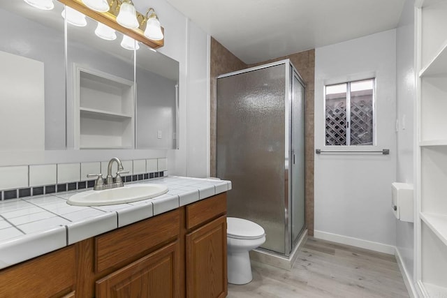 bathroom with hardwood / wood-style floors, vanity, toilet, tasteful backsplash, and a shower with shower door