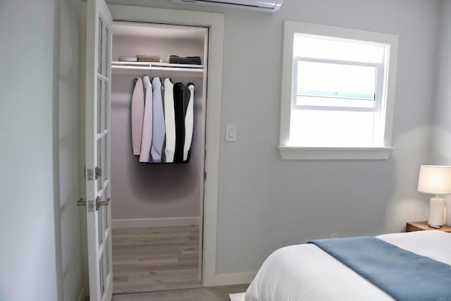 bedroom with a closet, a wall mounted air conditioner, and light hardwood / wood-style flooring