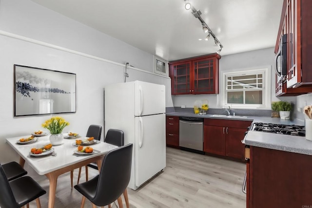 kitchen featuring sink, light hardwood / wood-style floors, track lighting, and appliances with stainless steel finishes