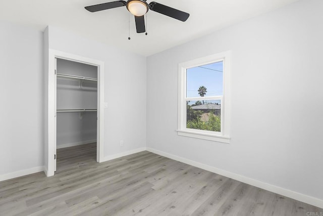 unfurnished bedroom with ceiling fan, light wood-type flooring, and a closet