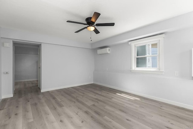 unfurnished bedroom featuring ceiling fan, an AC wall unit, light hardwood / wood-style flooring, and a closet