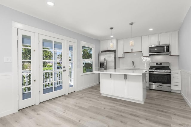 kitchen featuring hanging light fixtures, a center island, stainless steel appliances, and light hardwood / wood-style floors