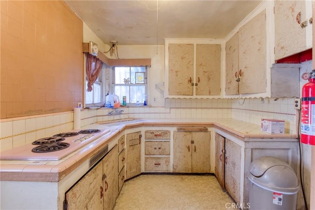 kitchen featuring tile countertops, decorative backsplash, and white gas stovetop