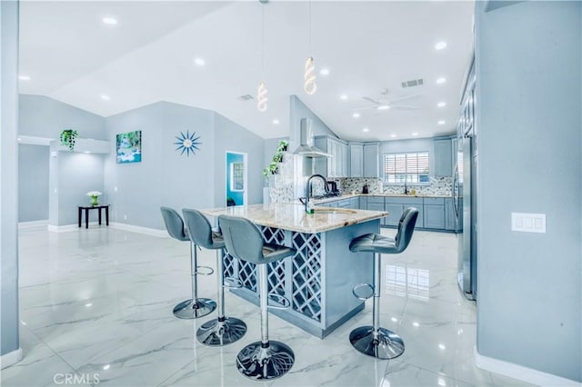 kitchen with gray cabinetry, light stone countertops, a kitchen breakfast bar, vaulted ceiling, and decorative light fixtures